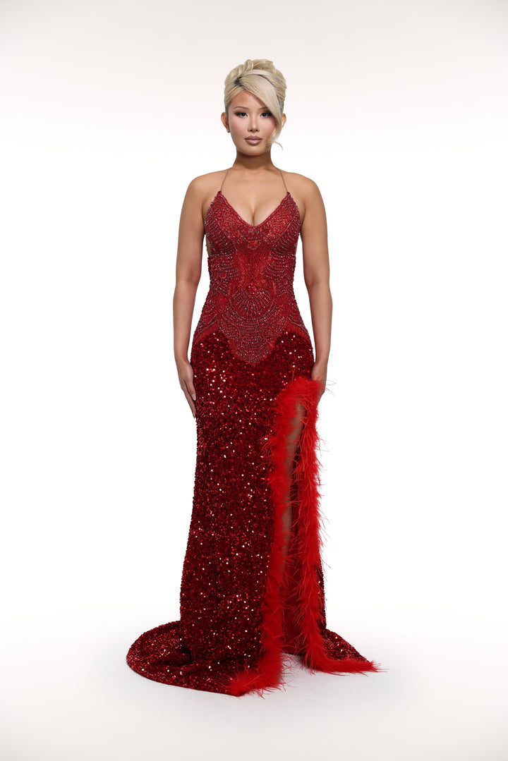Woman wearing a red sequin evening gown with a high slit on a white background
