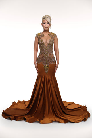 Woman wearing a brown evening gown with intricate detailing on a white background