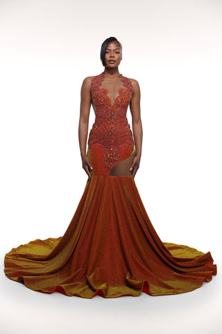 Woman wearing a rust-colored evening gown with intricate detailing on a white background