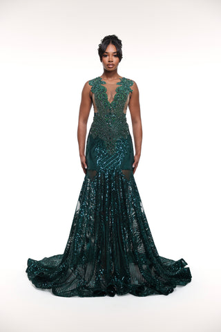 Woman wearing a dark green beaded evening gown on a white background