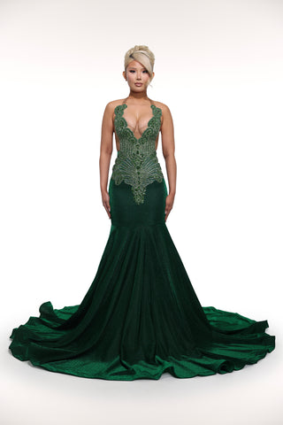 Woman wearing a green evening gown with intricate detailing on a white background